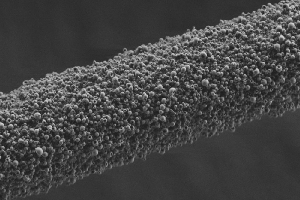 Shown at microscopic scale is a polyimide coating applied with electrospray deposition on bond wire used in electronics packaging. Image Credit: Paul Chiarot